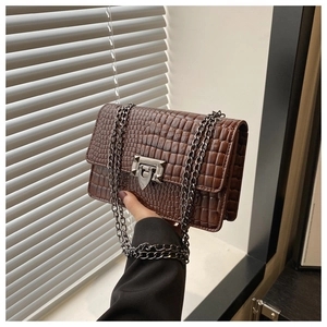 Close-up of brown crocodile texture handbag with silver twist lock and metal chain