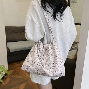 Sac fourre-tout en toile florale avec cordon porté par un mannequin dans un salon chic