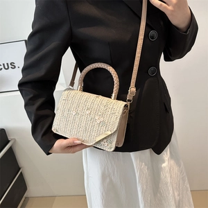 Sac en paille avec broderie florale et fermoir doré porté par un mannequin