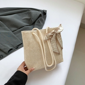 Detail of woven straw tote bag with V-pattern texture, cotton rope handle and decorative scarf