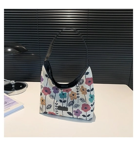 Macro view of floral tapestry tote with black leather straps and fashion label detail