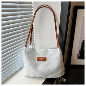 Close-up of white tote bag with geometric texture and brown leather strap details