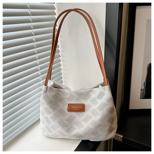 Detail of off-white tote bag with 3D geometric woven texture and brown leather strap