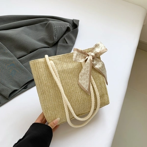 Detail of beige straw tote bag with V-shaped weave pattern and white braided handle
