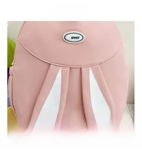 Detail of pink backpack with white rabbit ears and a blue SPORT logo patch