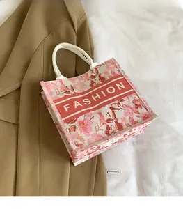 Détail du cabas en toile à fleurs roses avec logo Fashion et anses en corde blanche