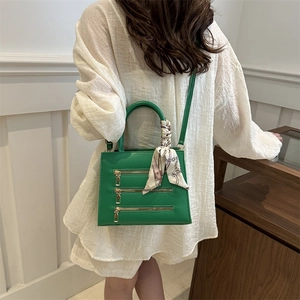 Green leather tote with three decorative zippers and floral scarf handle wrap