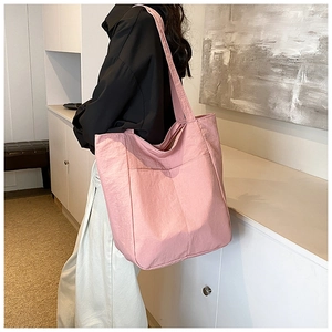 Detail of pink oversized tote bag featuring textured fabric and functional front pocket