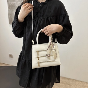 White leather crossbody tote with gold zippers and scarf handle detail on model
