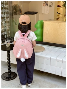Close-up of pink rabbit ears backpack for girls with a cute white pom-pom charm detail
