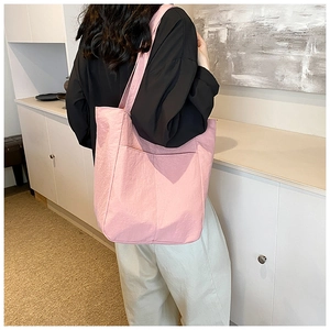 Pink nylon tote bag with dual front pockets shown worn as a large shoulder bag