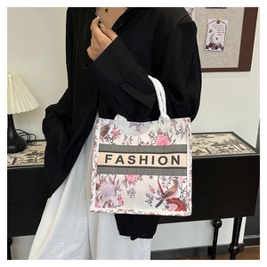 Gros plan détaillé d'un sac cabas en toile ethnique avec fleurs roses et motifs d'oiseaux