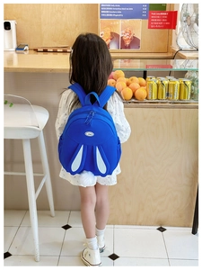 Detail of blue rabbit backpack for kids with long ears and fluffy pom-pom tail