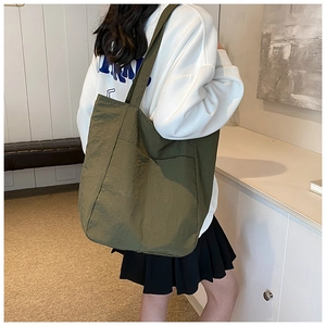 Detail of olive green large tote bag with nylon texture on shoulder of female model
