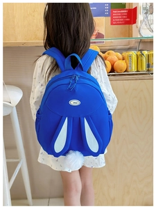 Detail of bright blue kids backpack with bunny ears and fuzzy tail on a young model