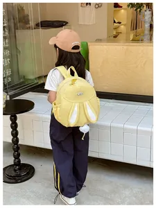 Detail showing plush rabbit tail and ears on a yellow girl's backpack for school