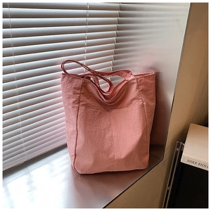 Detail of light pink tote bag with textured nylon fabric and large front pocket