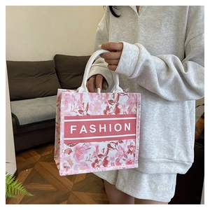 Détail du sac cabas en toile à fleurs roses avec logo FASHION et anses tressées