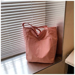 Detail of light pink pleated nylon tote bag with large front pocket and shoulder straps
