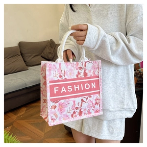 Détail du sac cabas en toile à fleurs roses avec anses en corde et logo FASHION central