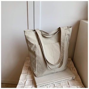 Detail view of large minimalist cream tote bag with wrinkled nylon texture on stone surface