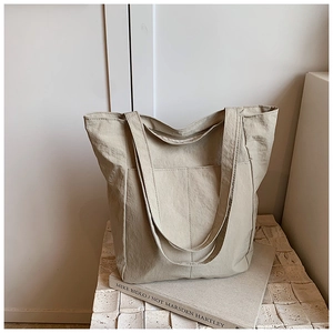 Detail of beige large capacity tote bag featuring nylon texture and front pocket