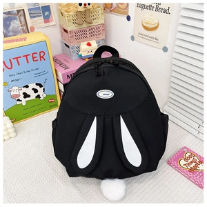 Close-up of black rabbit backpack with white ears, plush pom-pom tail, and side pockets