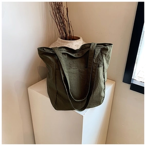 Detail of army green nylon tote bag on display stand showing texture and shoulder strap