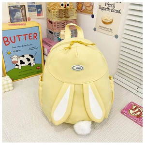 Detail of yellow rabbit-shaped backpack featuring white bunny ears and plush tail