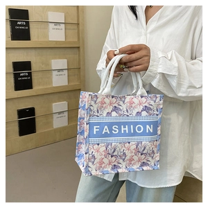 Détail du cabas floral avec bande de texte 'FASHION' bleue et anses en toile