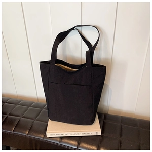 Detail view of large black canvas tote bag showing wide front pocket and inner lining