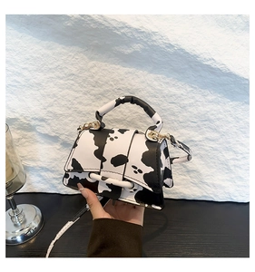 Détails du motif vache et de la boucle en métal doré sur un mini sac à bandoulière chic