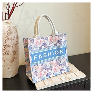 Gros plan d'un sac cabas en toile à fleurs avec des poignées tissées blanches