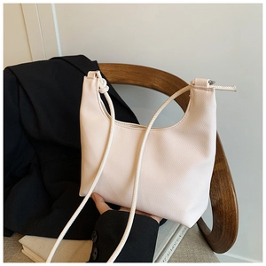 Detail of minimalist cream hobo bag with pebble leather texture and knotted strap