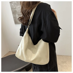 Detail of cream white tote bag featuring geometric patchwork stitching and shoulder strap