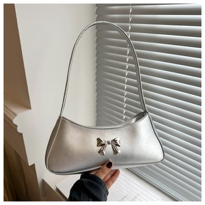 Detail of silver metallic baguette bag featuring a polished bow buckle and leather texture