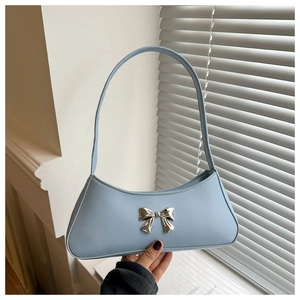 Detailed view of light blue baguette bag featuring a silver metal bow accent and smooth finish