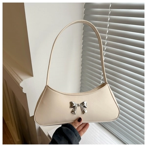 Detail of cream white baguette bag with silver bow charm and elegant shoulder strap