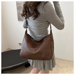 Detail of vintage dark brown faux leather tote bag with soft pleated texture and shoulder strap