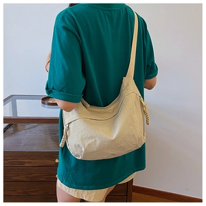 Detail of beige crossbody tote bag with wide strap and textured rope zipper puller