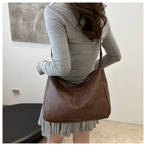 Rear view of model wearing a large dark brown vintage tote bag with PU leather texture