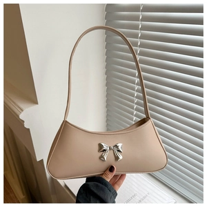 Detail of light beige PU leather baguette bag featuring a 3D silver bow metal buckle
