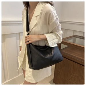 Chic black crescent shoulder bag with wide strap and gold ring detail on model