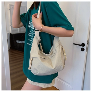 Close-up of beige nylon shoulder bag featuring unique woven rope zipper detail