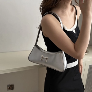 Silver metallic baguette shoulder bag with a bow detail on a stylish female model