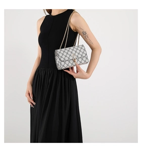 Detail of light grey geometric print crossbody bag with gold chain and oval metal lock