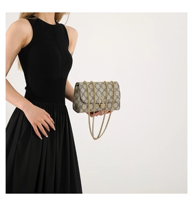 Detail of vintage monogram crossbody bag with gold chain strap on black dress
