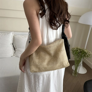 Woven straw tote bag in beige with black shoulder straps for summer beach travel fashion