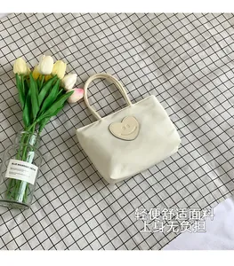 Detail of cream bucket bag with heart smile patch on checkered background
