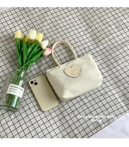 Detail view of cream white bucket bag with heart emoji patch on checkered background